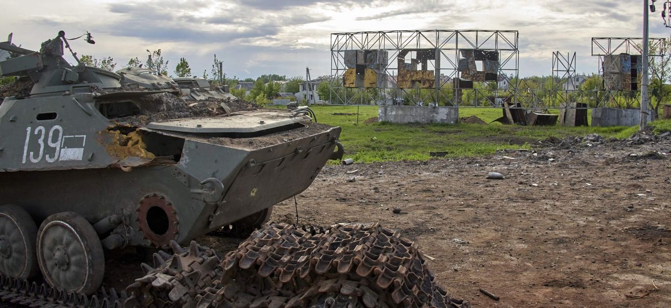 A destroyed military vehicle in front of a damaged 'Kharkiv' sign on the outskirts of Kharkiv, Ukraine, Photo: PAP