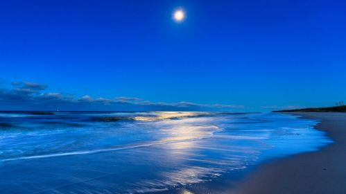 Błękitne morze i błękitne niebo jasno oświetlone nisko położonym Słońcem.