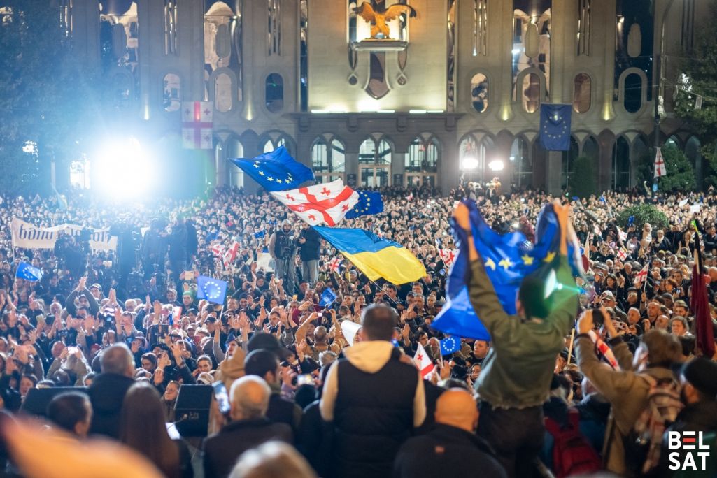 Грузіны трымаюць сцяг ЕЗ перад будынкам парламенту падчас мітынгу супраць папярэдніх вынікаў парламенцкіх выбараў, паводле якіх кіруючая партыя «Грузінская мара» застаецца ва ўладзе і зможа сфарміраваць урад у чацвёрты раз. Прэзідэнтка Грузіі Саламэ Зурабішвілі адмовілася прызнаваць вынікі выбараў, назваўшы цяперашні ўрад краіны нелегітымным. Апазіцыя патрабуе міжнароднага расследавання і новых выбараў, а таксама доступу да электроннай інфармацыі ЦВК. Тбілісі, Грузія. 28 кастрычніка 2024 года. Фота: Белсат