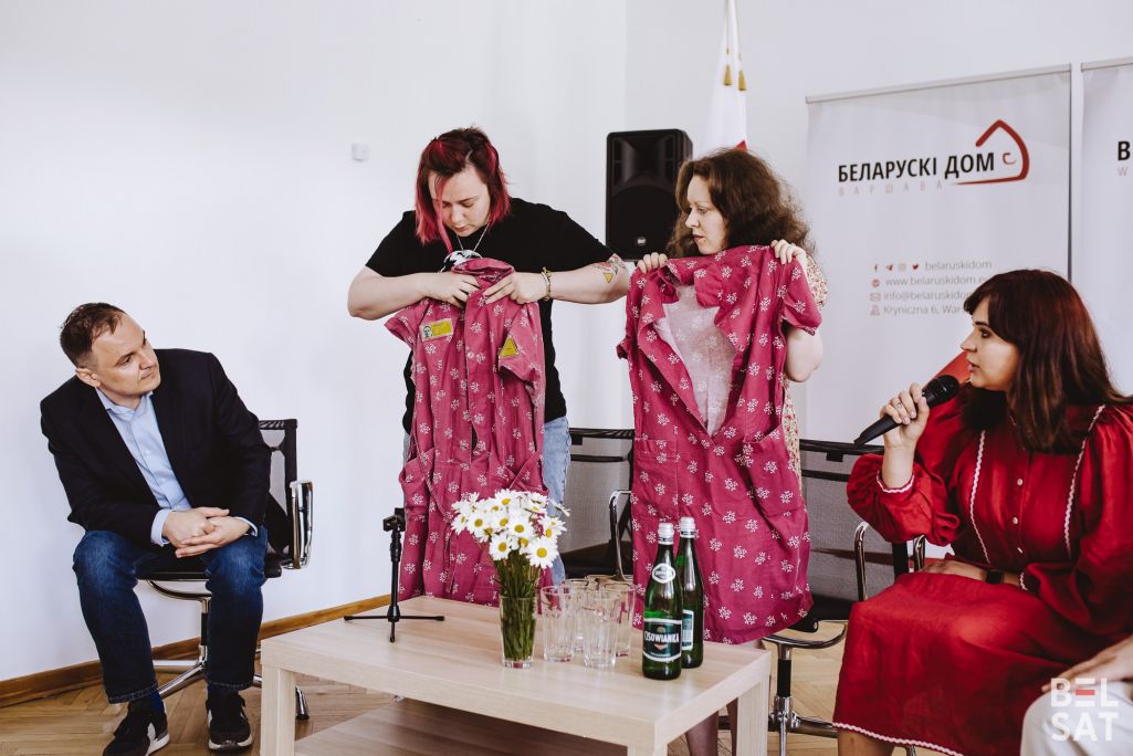 Былыя палітзняволеныя Дар’я Афанасьева і Міа Міткевіч паказваюць сукенкі, якія яны насілі ў калоніі. У Беларускім доме прайшла прэс-канферэнцыя з нагоды Дня палітвязня. Варшава, Польшча. 21 траўня 2024 года. (Фота: Белсат)