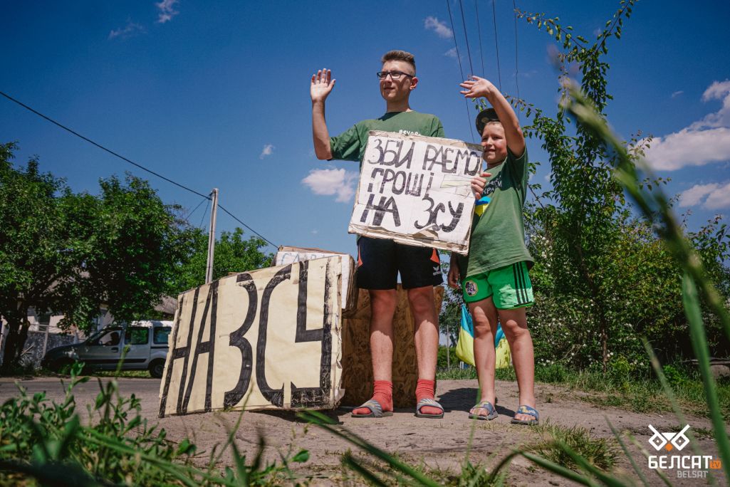 Алег і Андрэй махаюць машынам, якія праязджаюць па іхнай вуліцы, каб прыцягнуць увагу кіроўцаў. (Фота: Алесь Усцінаў / Белсат)