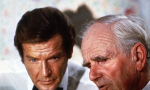 Роджер Мур у ролі Джеймса Бонда та Десмонд Ллевелін у ролі Q (псевдонім керівника відділу досліджень і розробок MI6). У фільмі «Восьминіжка» (1983) вони монтують передавач у яйце Фаберже. Дозволяють агенту 007, щоб після п’янкої ночі викрала його Магда – коханка афганського принца на вигнанні, яка планує контрабандою провезти коштовності до Індії. Фото United Artists, Danjaq, EON Productions, Metro-Goldwyn-Mayers (MGM)