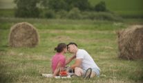 Kadr z programu TVP „Rolnik szuka żony”. Na zdjęciu rolniczka Wiktoria z kandydatem Adamem. Para znajduje się na polu wśród belek siana.