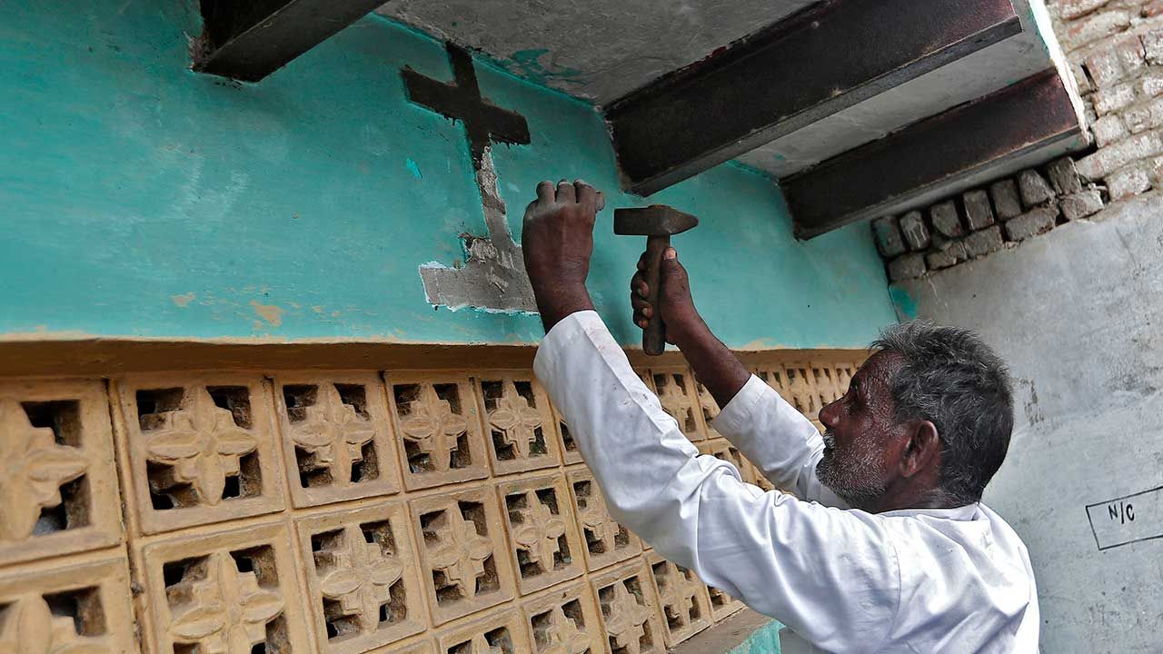 Mężczyzna usuwa krzyż z wejścia do domu po konwersji z chrześcijaństwa na hinduizm (fot. REUTERS/Adnan Abidi)