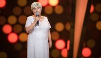 Ubrana w jasną, świecącą sukienkę Maria Stolińska występuje w programie „The Voice Senior”, śpiewając na scenie „Bésame mucho” Consuela Velázqueza.