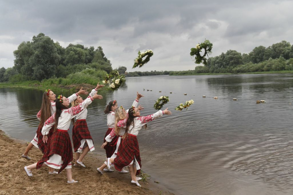 Беларускі ў традыцыйных нацыянальных строях кідаюць вянкі ў ваду ракі Бярэзіна на Івана Купалу, старажытнае свята ў гонар летняга сонцастаяння, у вёсцы Парычы, Беларусь. 6 ліпеня 2022 года. Фота: Viktor Drachev / AP Photo / East News