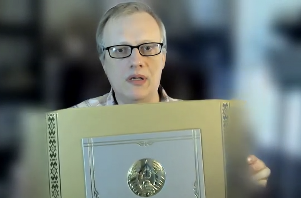 Yury Zyankovich holds a box of chocolates from Alyaksandr Lukashenka. Screenshot: Belsat